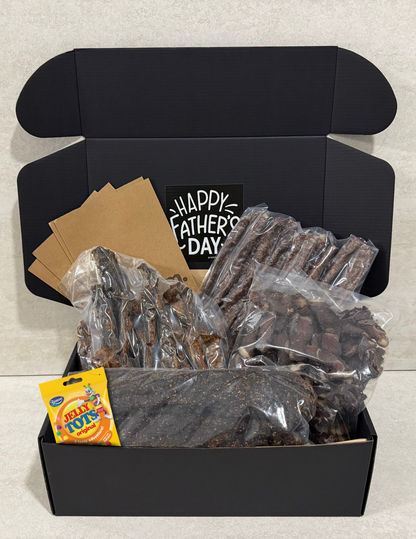 Black box with biltong, droewors hot chilli stokkies, jelly tots, and 'Happy Father's Day' card on a light gray background