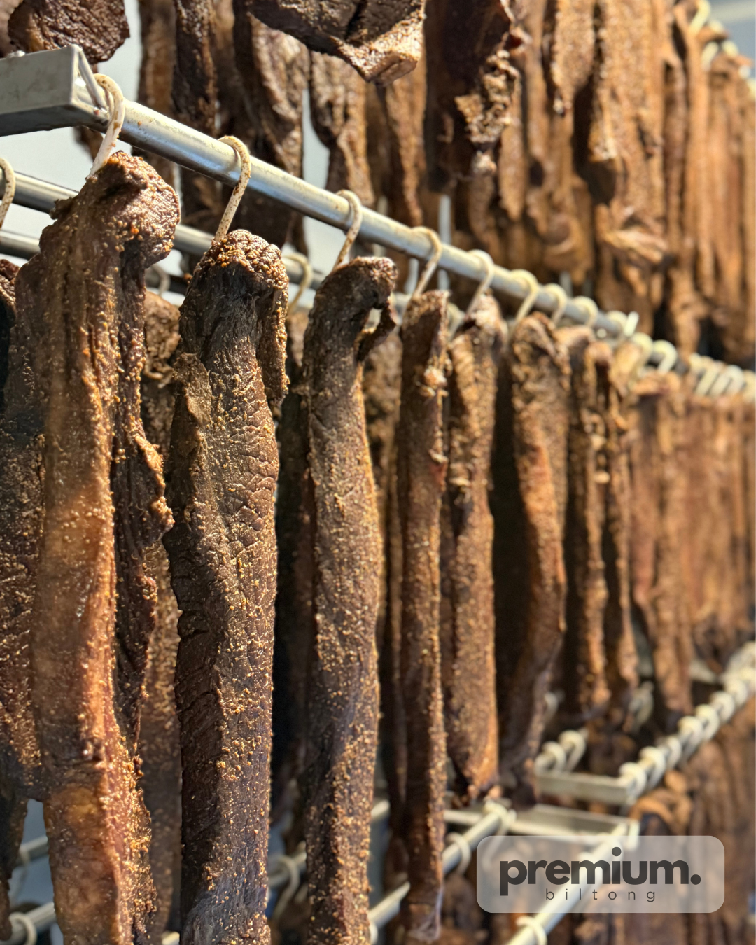 Drying biltong hanging on a rack with 'premium' branding.